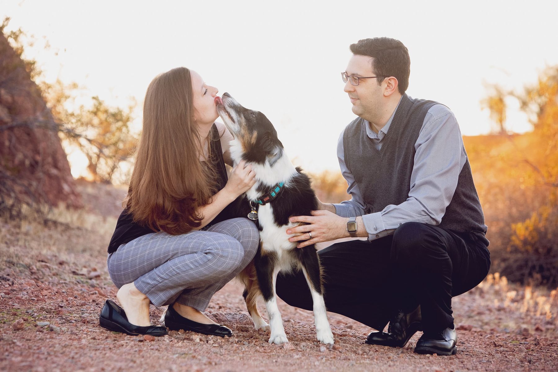 Dr. Michael Berman and Dr. Katie Kitchen crouched with their dog on a Sonoran desert trail at golden hour
